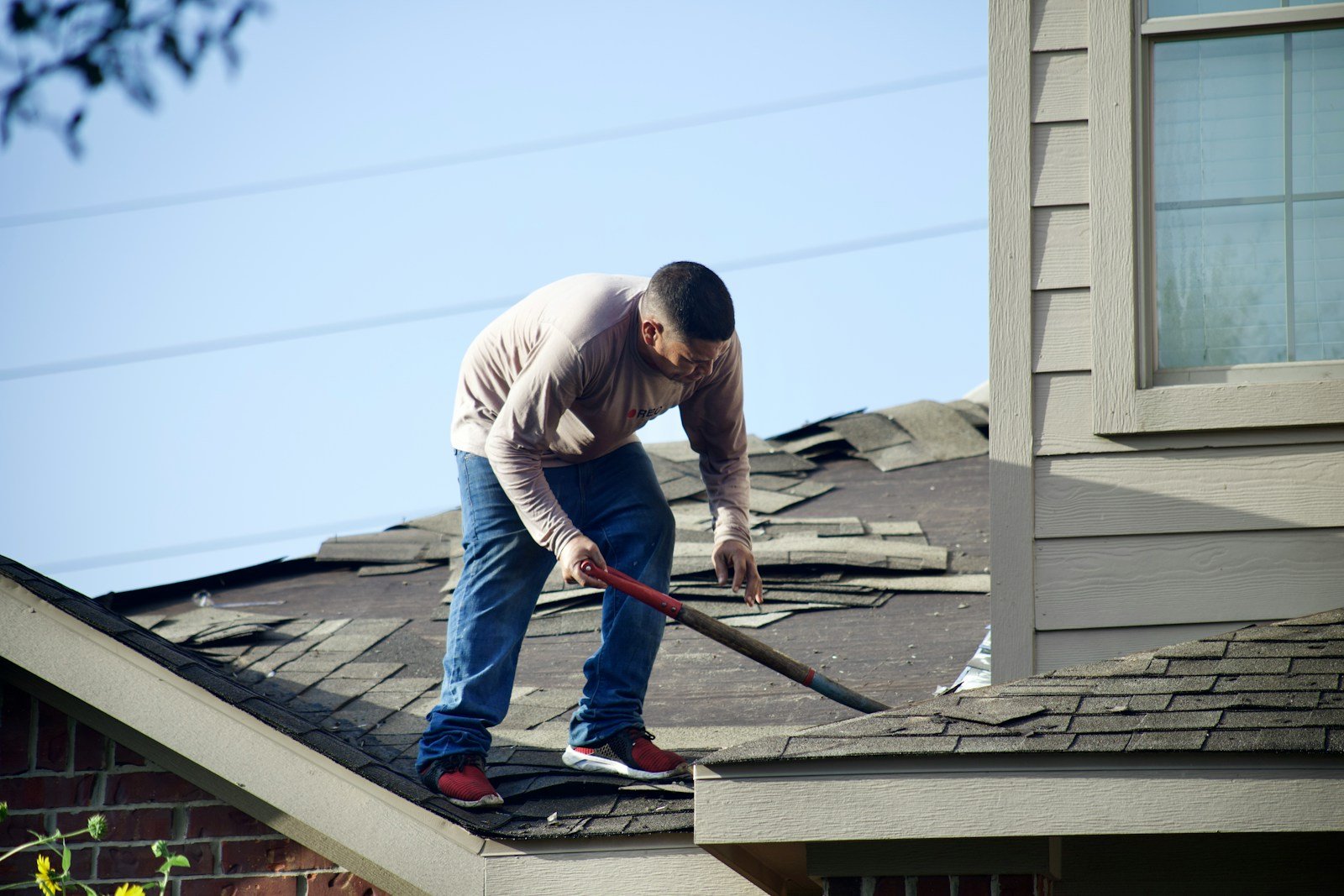 a man with a hammer on top of a roof for repairing roof